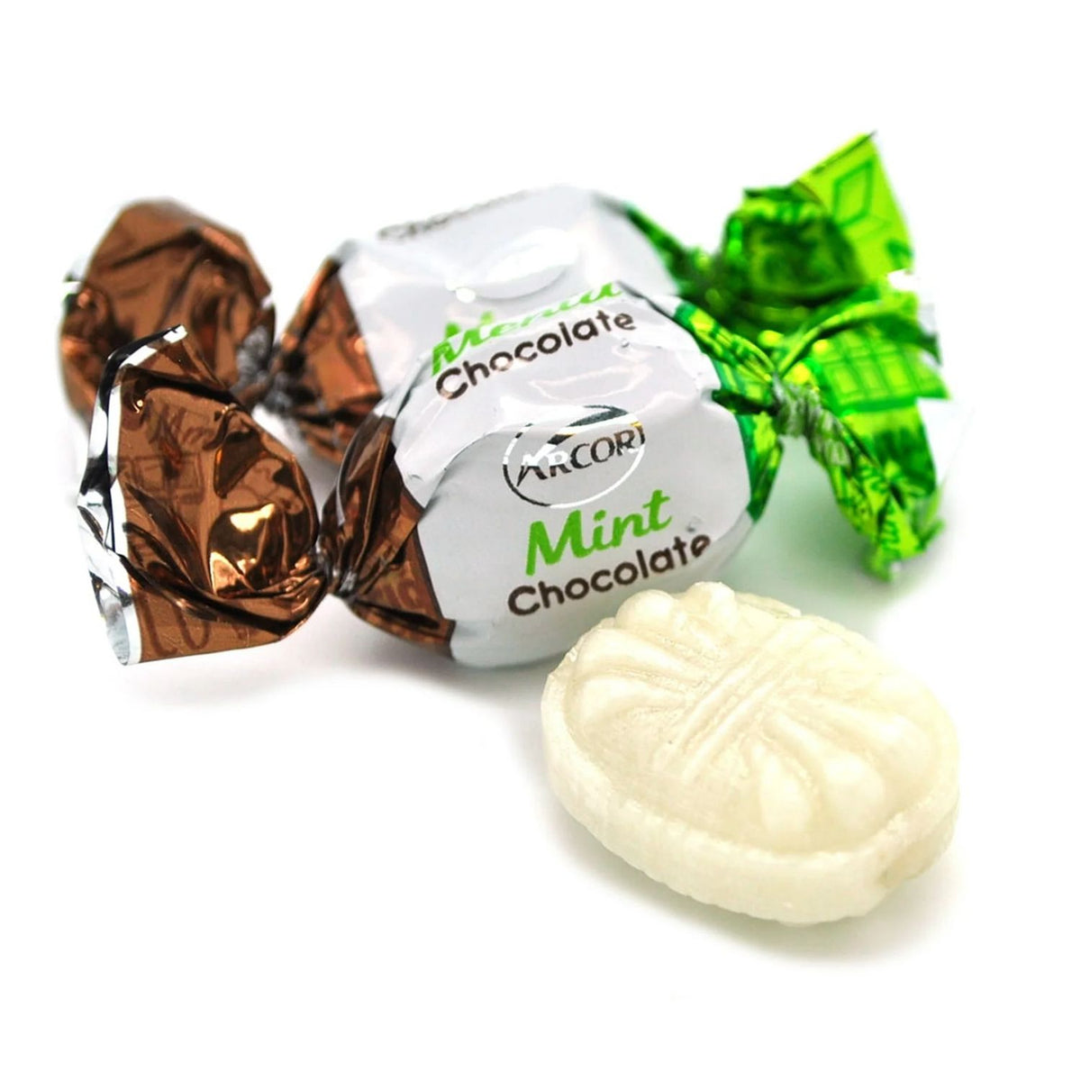 Three wrapped mint chocolates with silver foil wrappers in brown, white, and green, alongside one unwrapped white oval mint chocolate in front, on a white background.