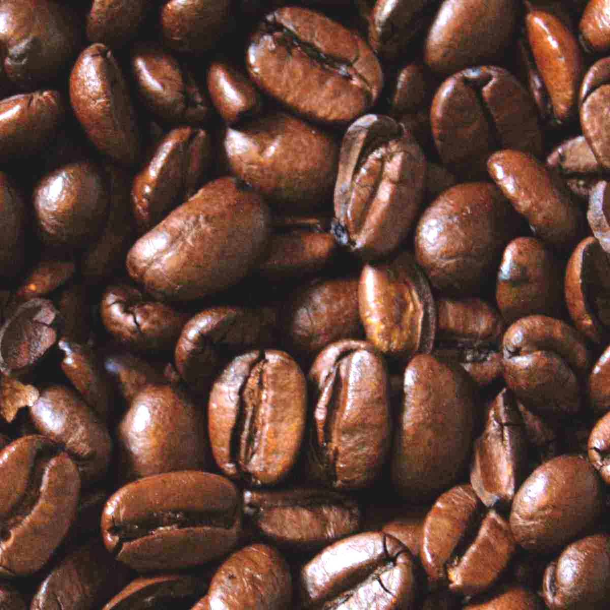 A close-up, top-down view of roasted coffee beans filling the entire frame, showing their rich dark brown color and textured surfaces.