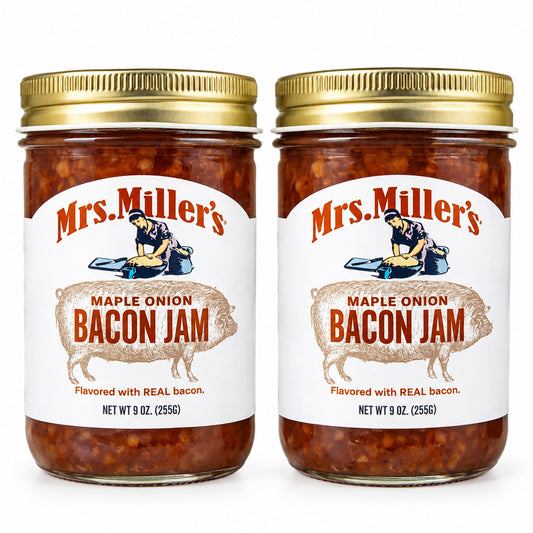  Two clear glass jars of Mrs. Miller's Maple Onion Bacon Jam with gold lids are displayed side-by-side on a white background.